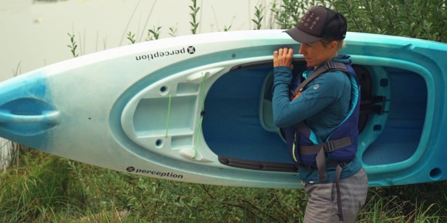 a kayaker carrying their kayak on their own