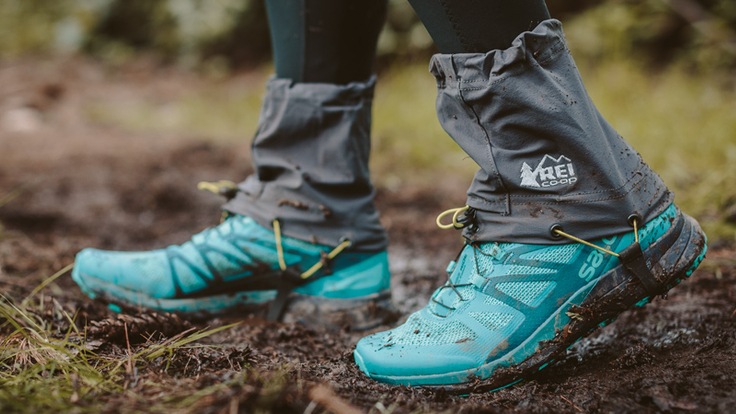 the feet of trailer runner, on the trail, with gaiters on