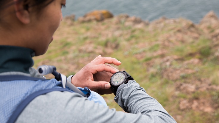 Trail runner pausing to check some readings on her fitness watch