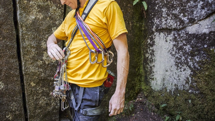 Climber inspects his gear rack of climbing equipment
