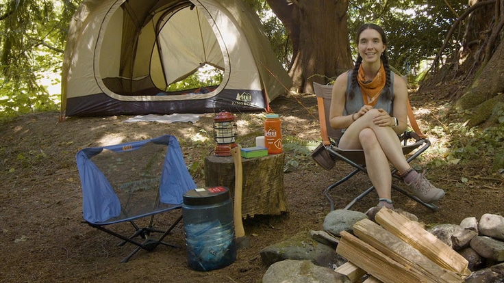 A woman sitting in a camp chair at her campsite
