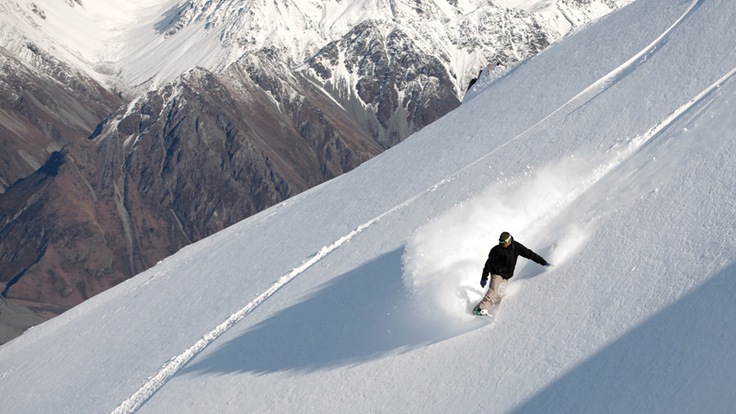 A snowboarder riding powder on a mountainside