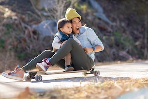 A mom and her young child sit atop a skateboard