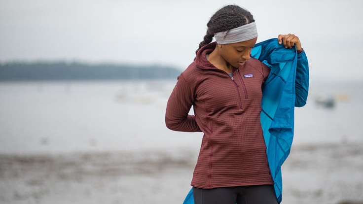 Woman puts on shell over fleece jacket.