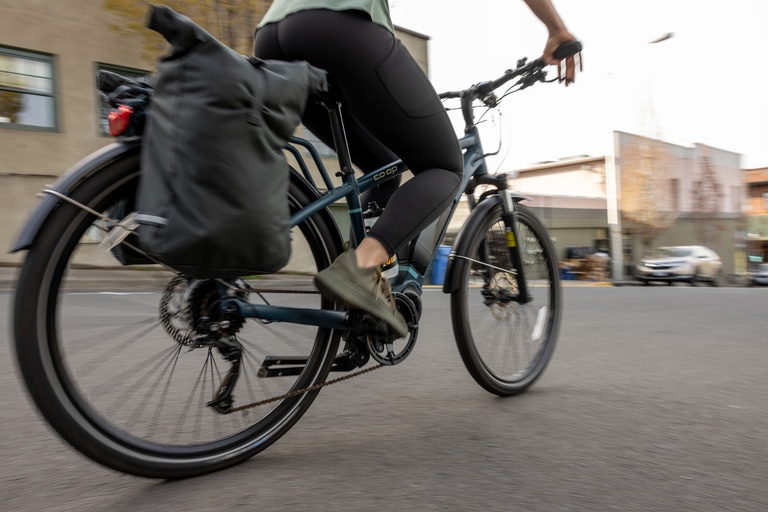 A cyclist stores gear in panniers, which are fitted on the back of the ebike.