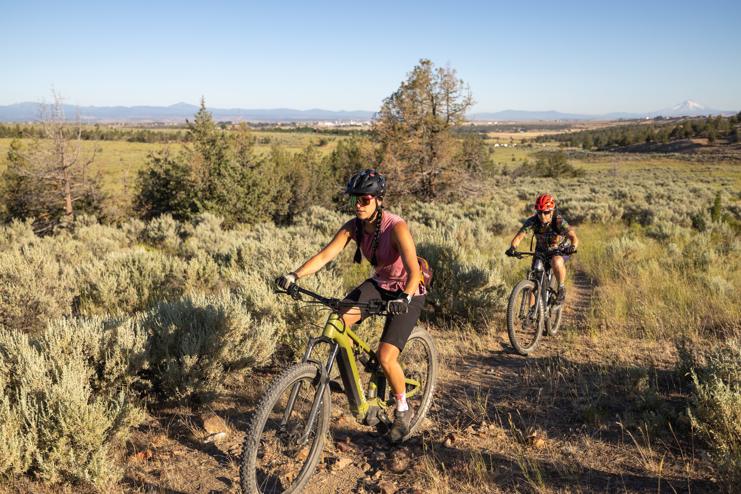 Two mountain bike riders cruise a dirt path using an electric mountain bike