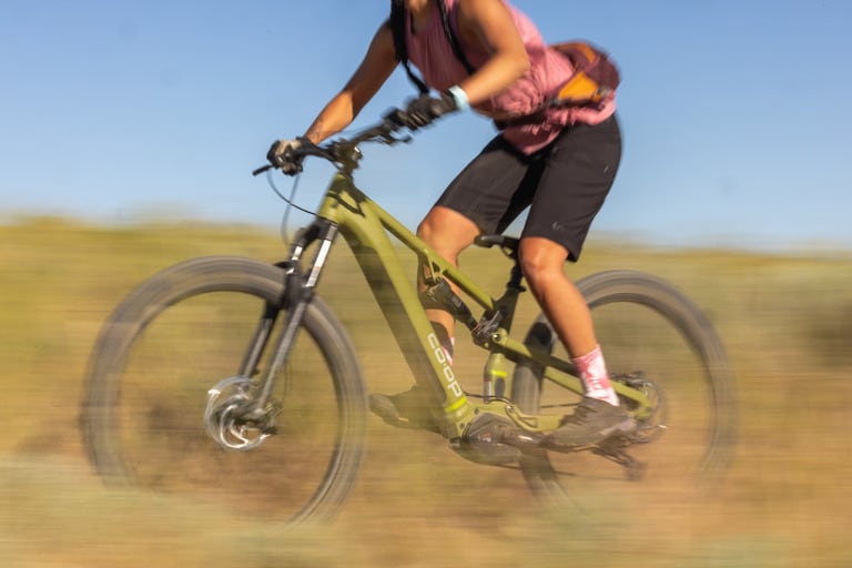A mountain biker wearing black loose mountain bike shorts rides a trail