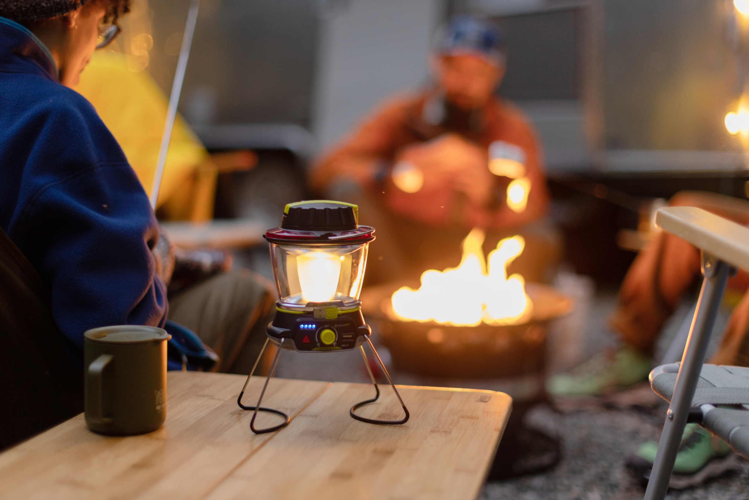 A camp lantern provides extra lighting around the campfire