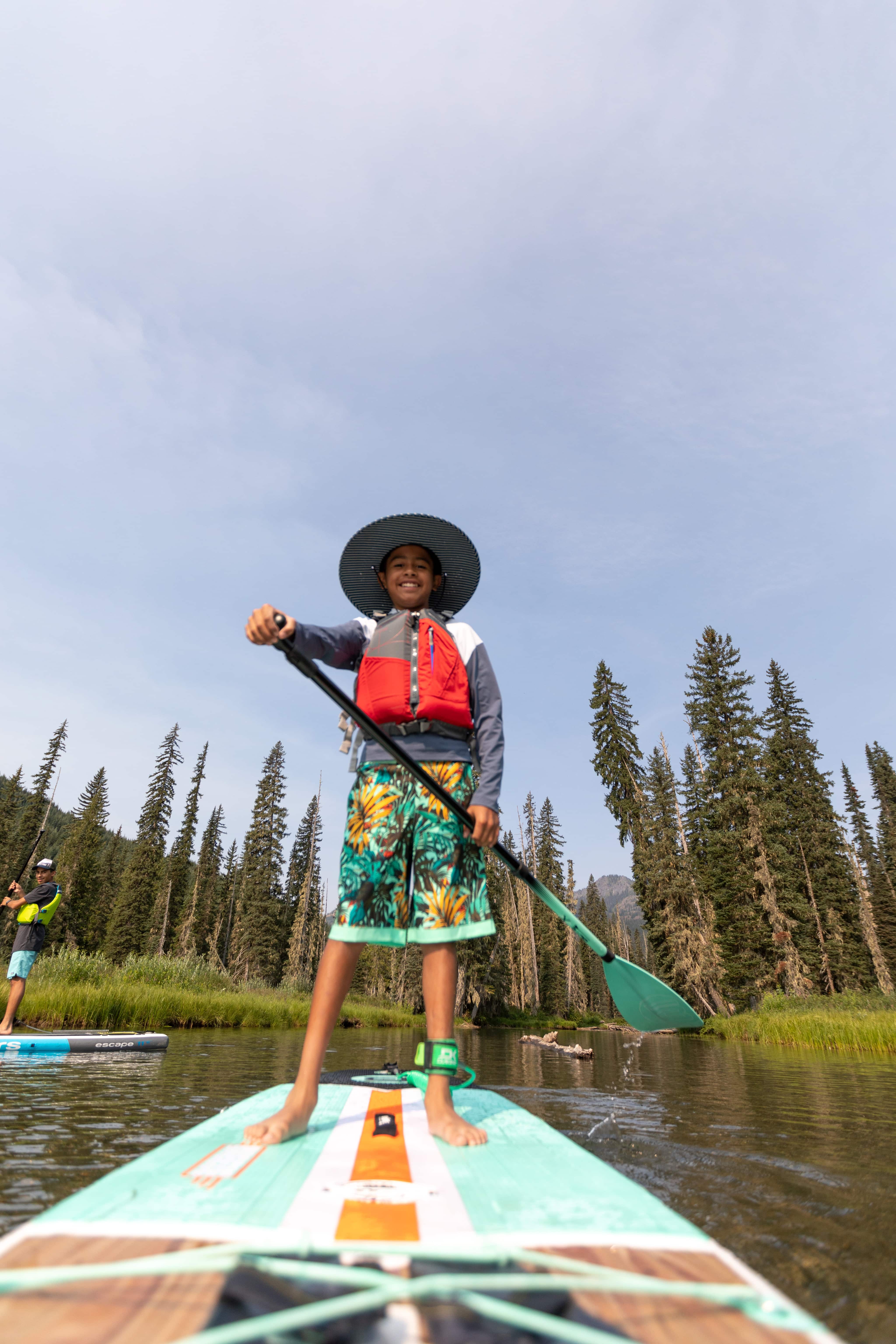 A person stands on a paddle board and smiles for the camera.
