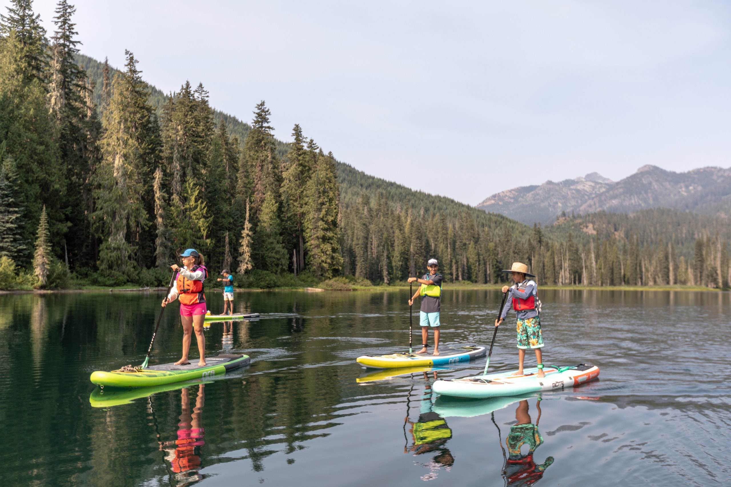 Three people on stand up paddle boards on a lake