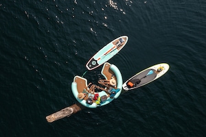 Group lounges on the water on a float with their paddle boards nearby