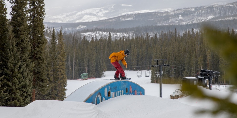 A snowboarder does a trick on a feature in a terrain park