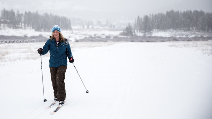 a smiling cross-country skier in a snowy landscape