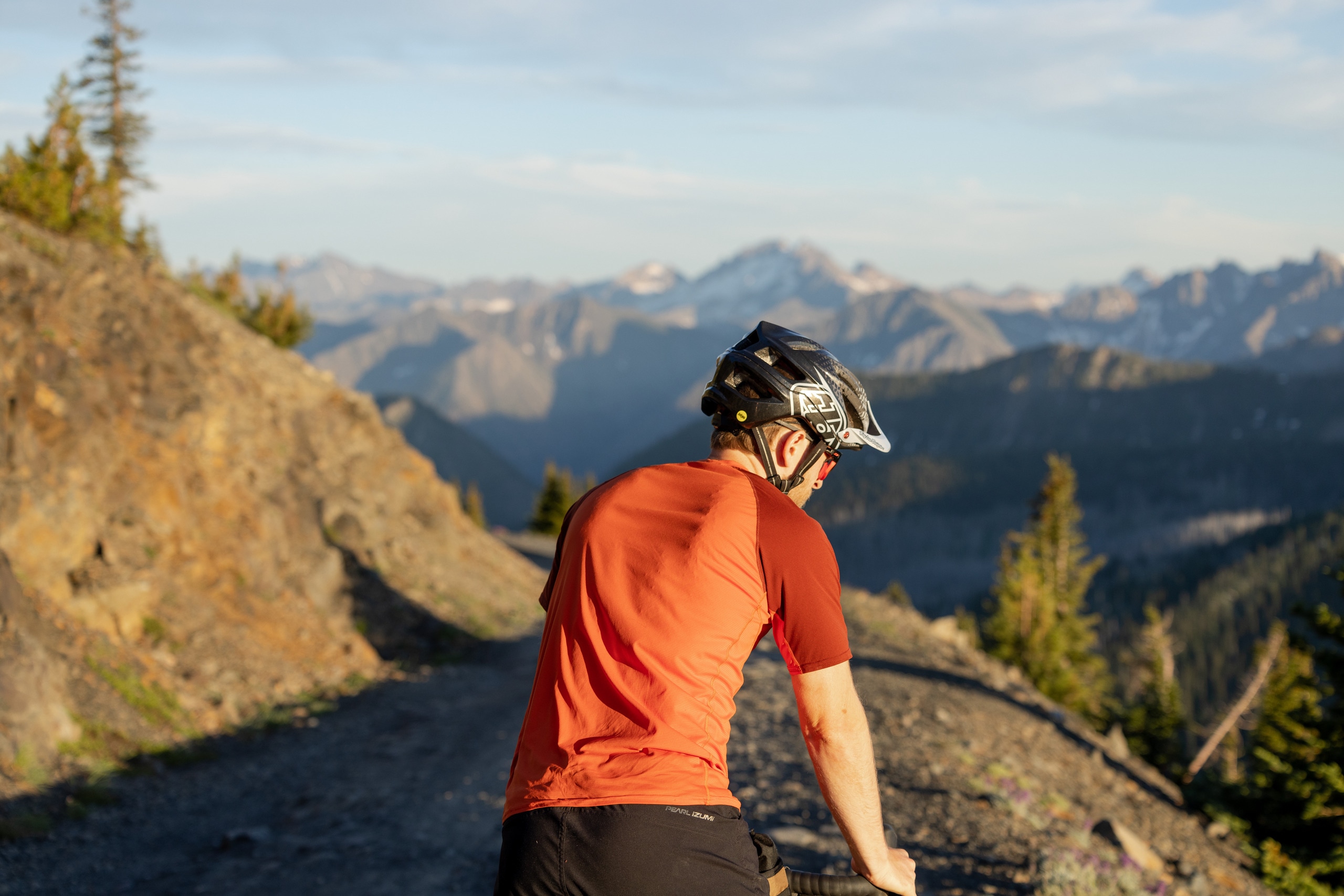 A cyclist with bike helmet stops at side of gravel round