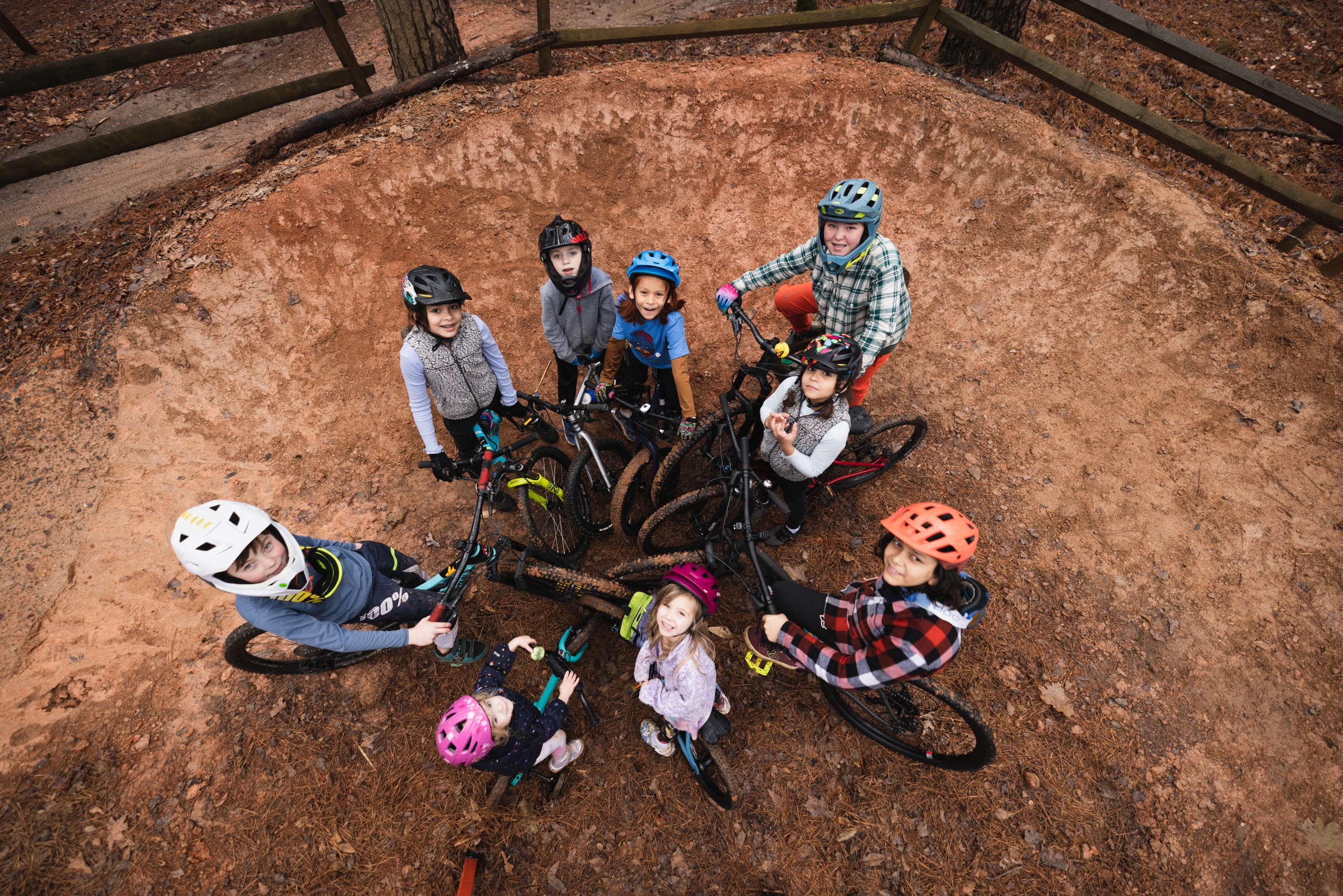 9 kids on their bikes gather in a center and look up at the sky