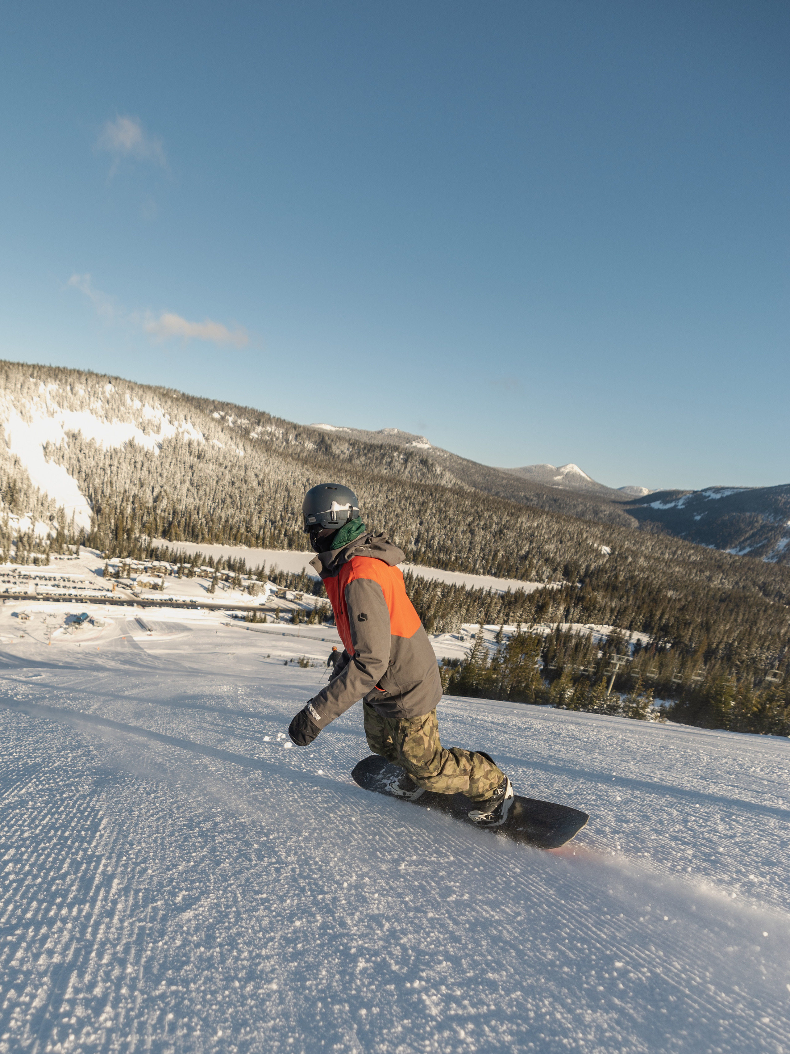 A person snowboards down the slope at a ski resort