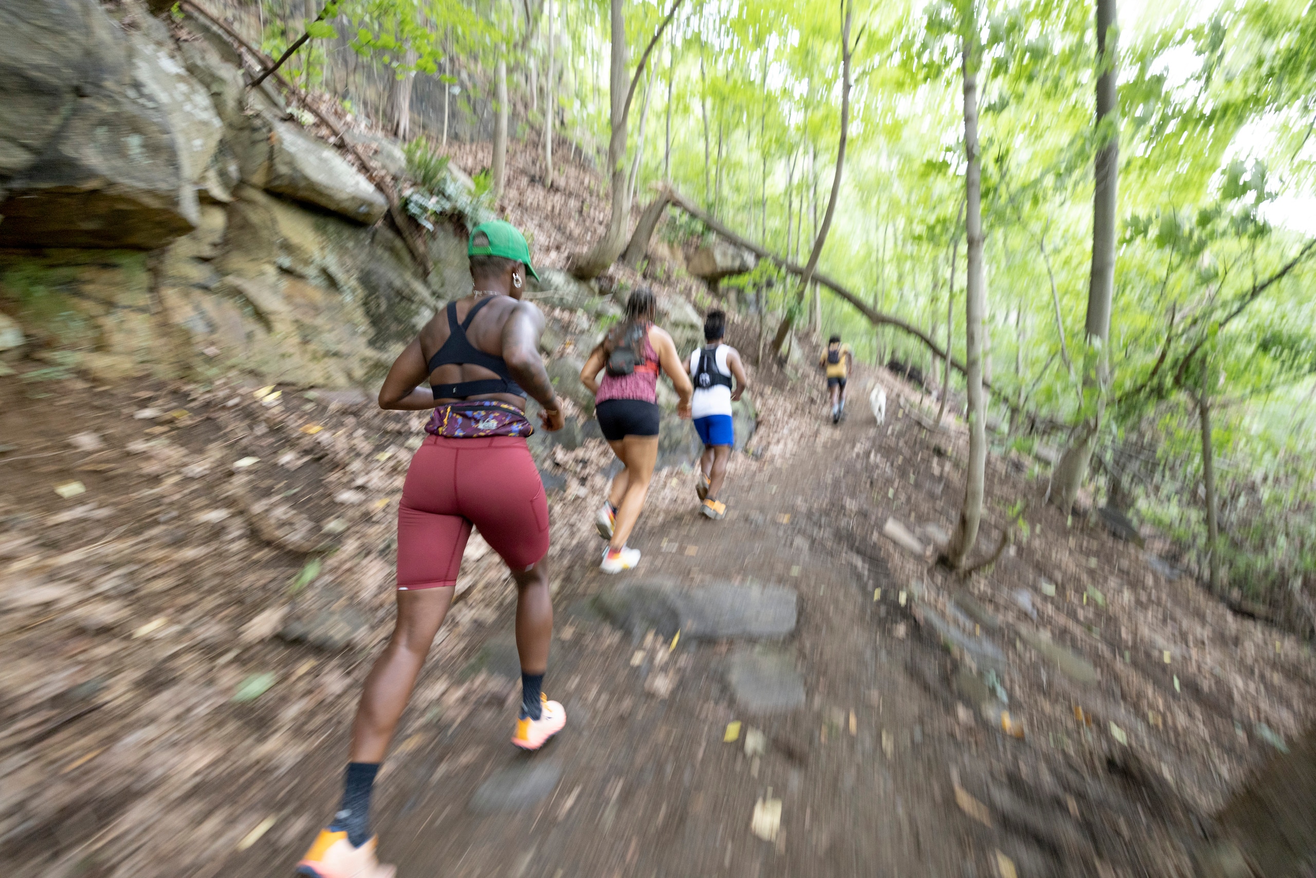 A group of runners running uphill on a trail