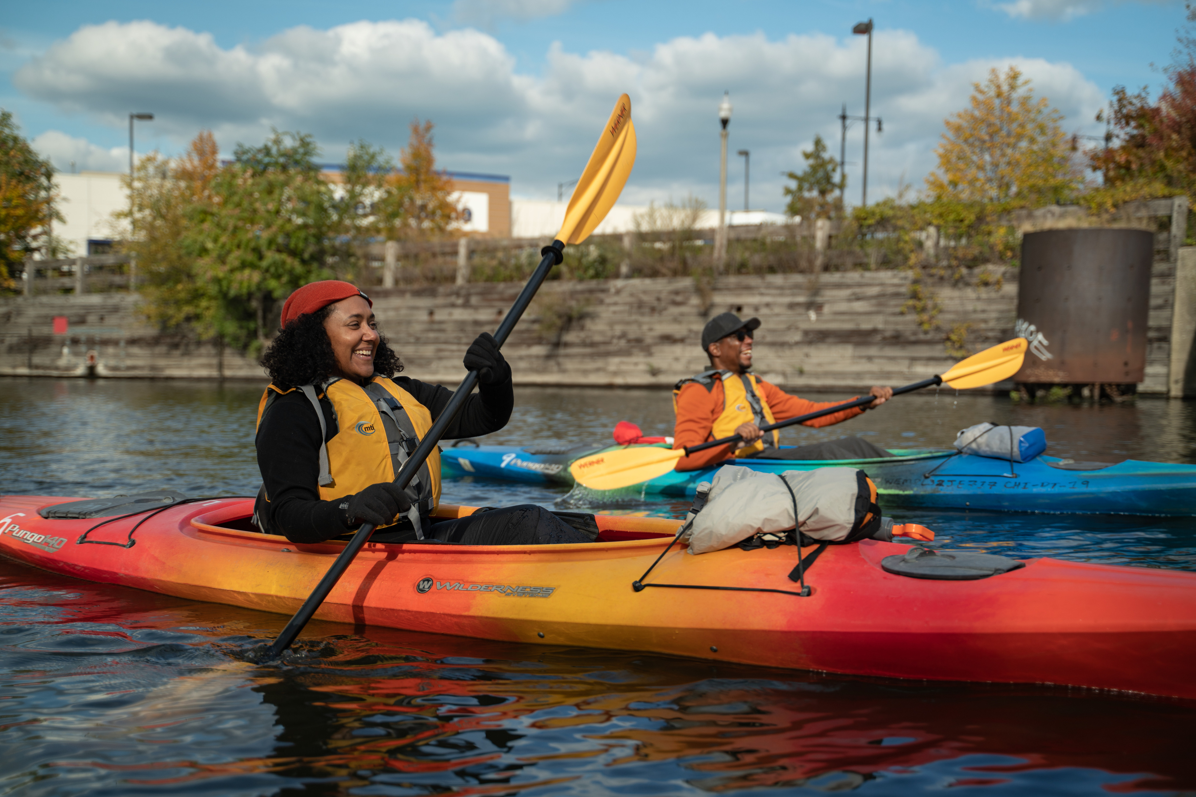 2 people enjoying kayaking on a lake near a city