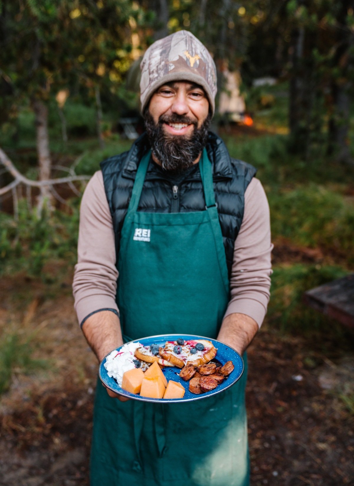 Person wearing apron holding plate of breakfast food