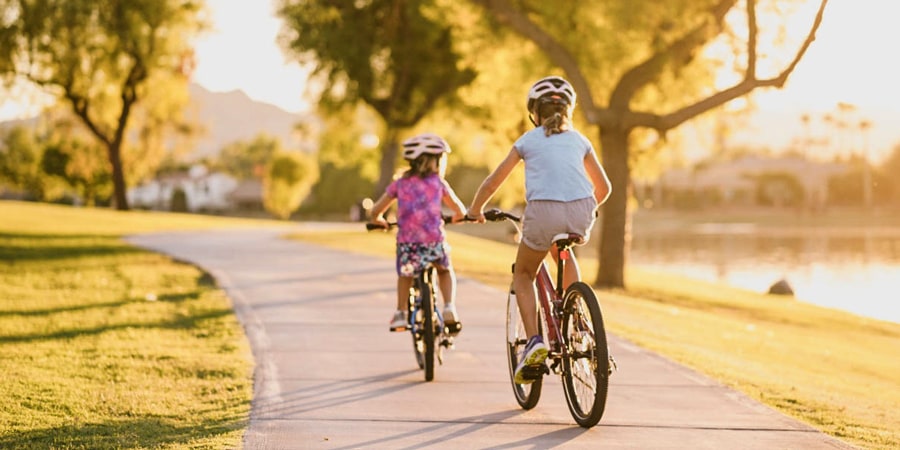 two kids on bikes riding off into the sunset