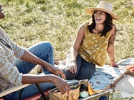 People relaxing on the gound in front of the sun shade