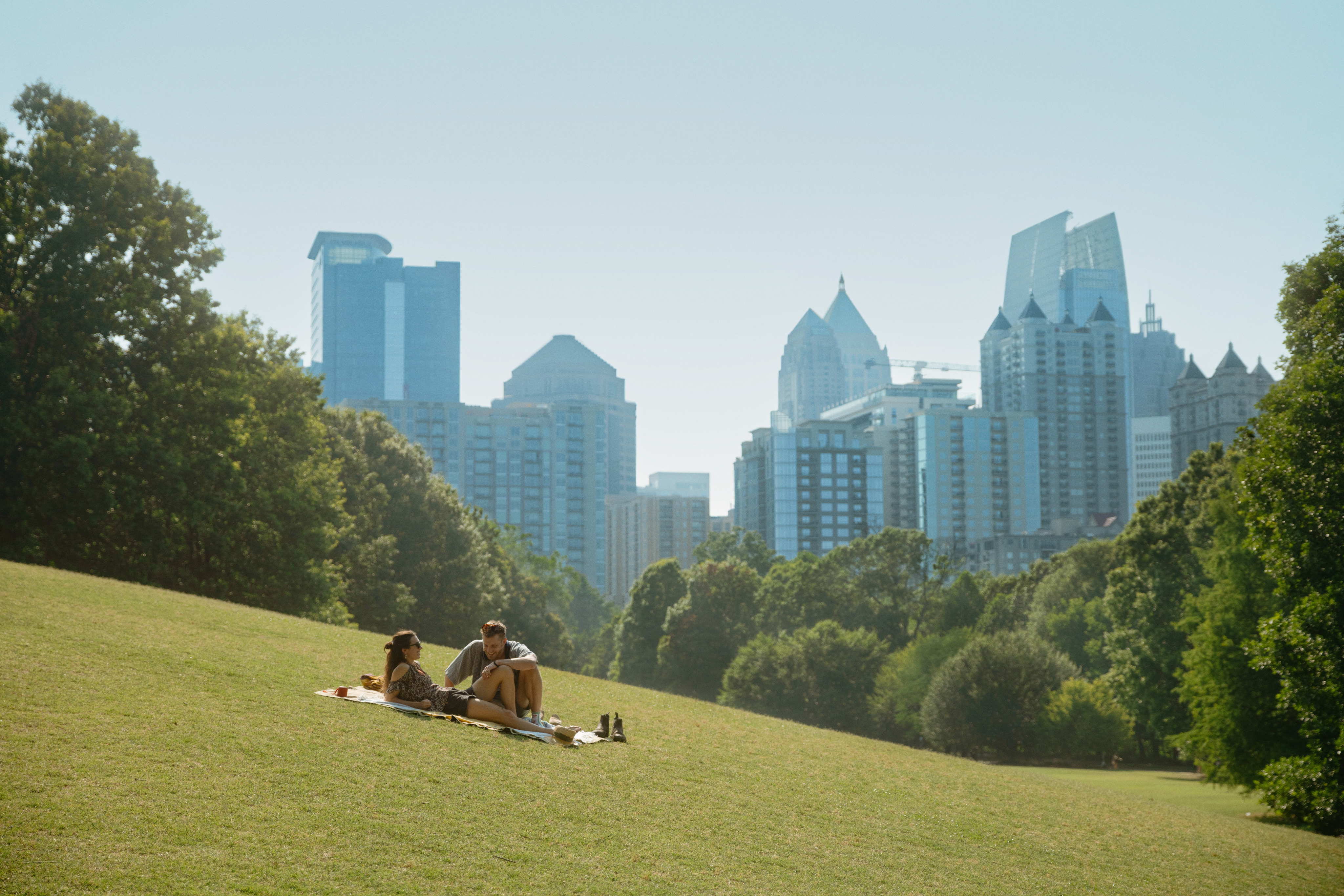 Urban greenscape with people picnicking and city skyline in the background