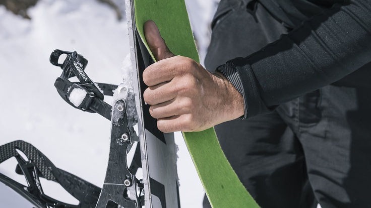 a snowboarder attaching skins to their splitboard