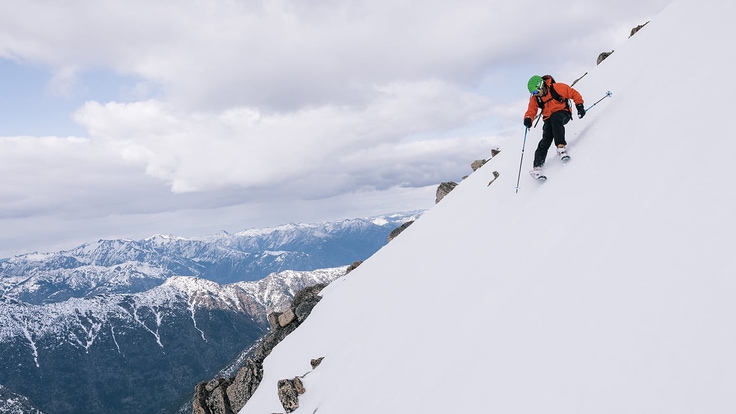 Skier makes turns down a steep slope