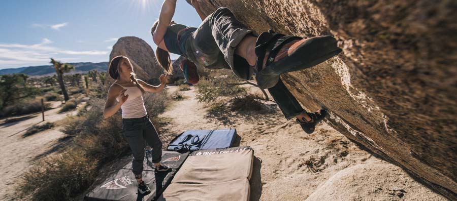 dois alpinistas começam suas Pedras em um deserto sudoeste, com seus crash pads dispostos