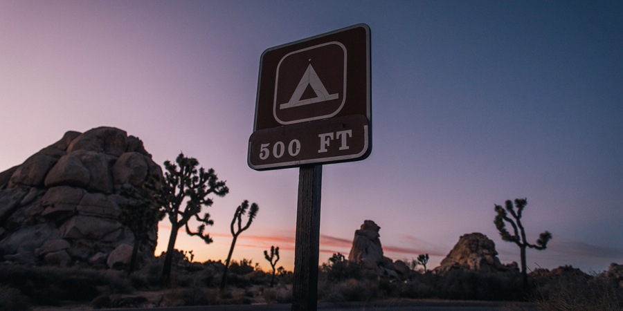 a campground sign along the side of the road at sunset