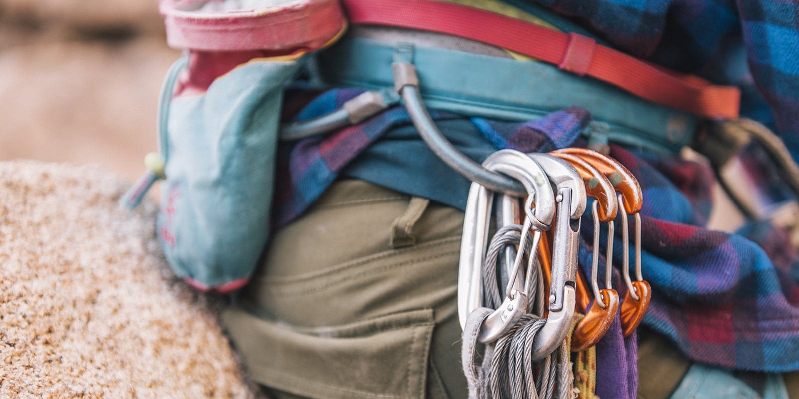 Close-up photo of four carabiners hanging off of the climbing harness a person is wearing
