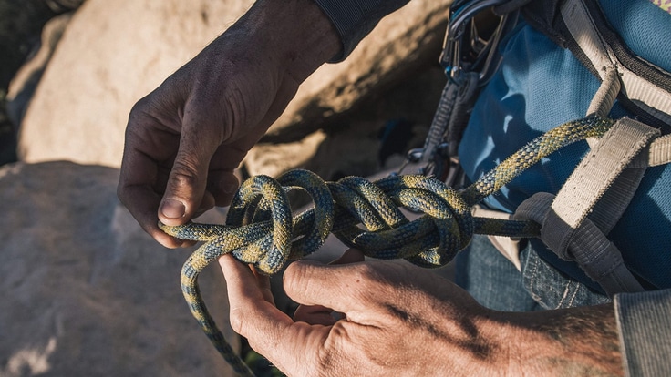a rock climber tying a knot into their harness