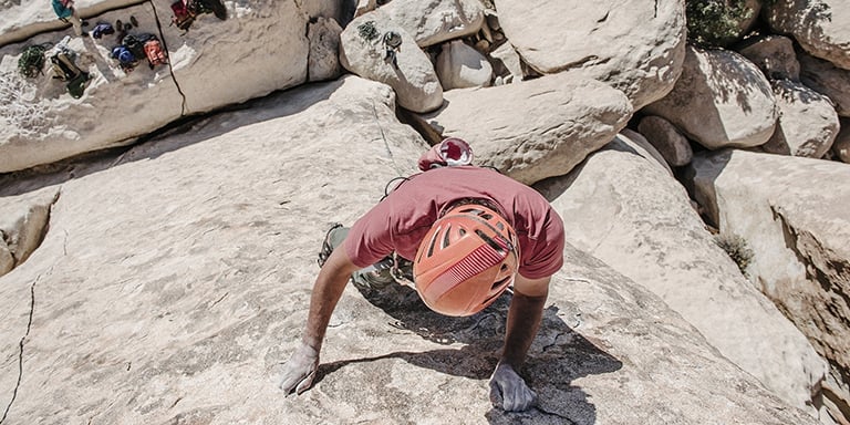 View from above as man climbs up rock face