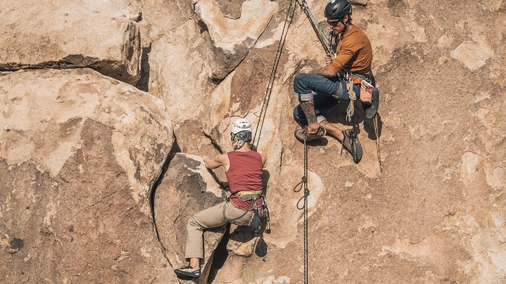 Two rock climbers climbing a rock face.