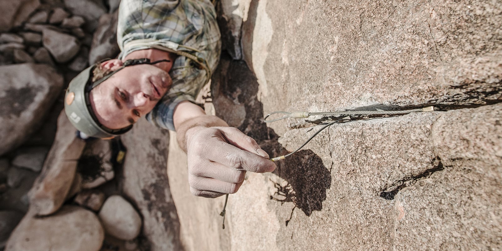A climber set a pro placement, also known as protection gear, in a rock face