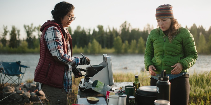 two campers preparing a meal at the campground