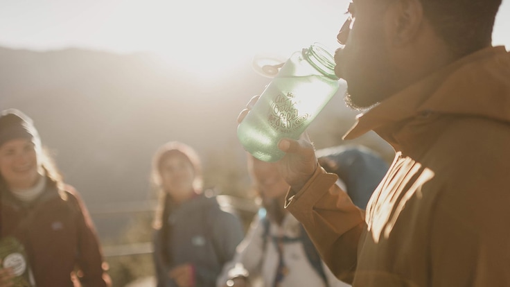 a hiker drinking from a clear water bottle