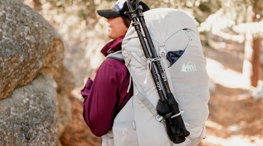 backpacker with a pair of adjustable trekking poles strapped to her pack