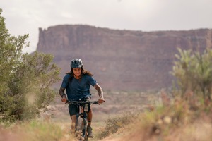 A cyclist biking on a trail wearing a helmet