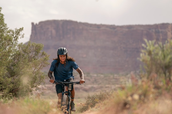 A cyclist biking on a trail wearing a helmet