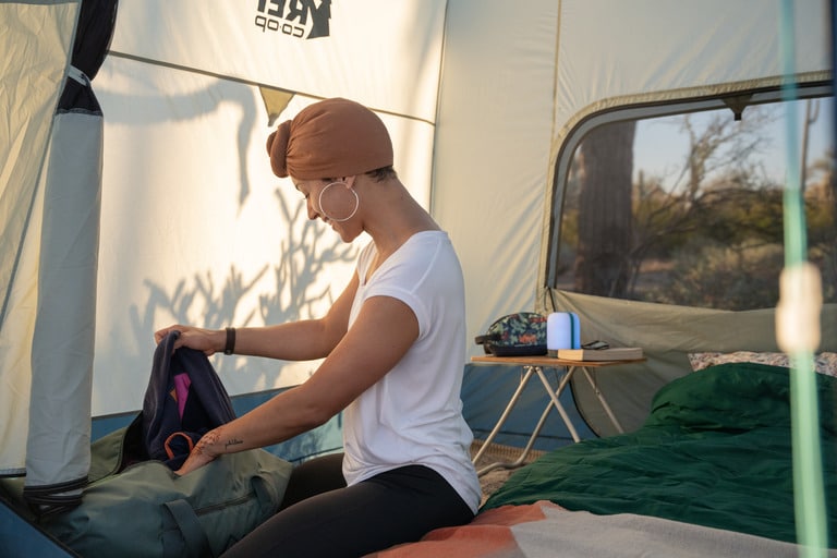 A woman rifles through her gear inside a tent