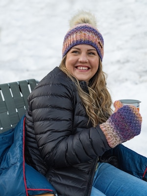 A person holds a coffee mug outside in the snow.