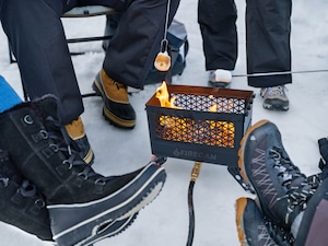 A group of people sit around a fire pit roasting marshmallows.
