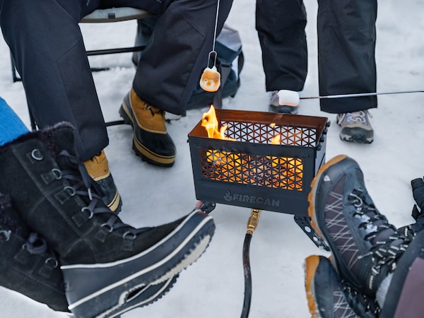A group of people sit around a fire pit roasting marshmallows.