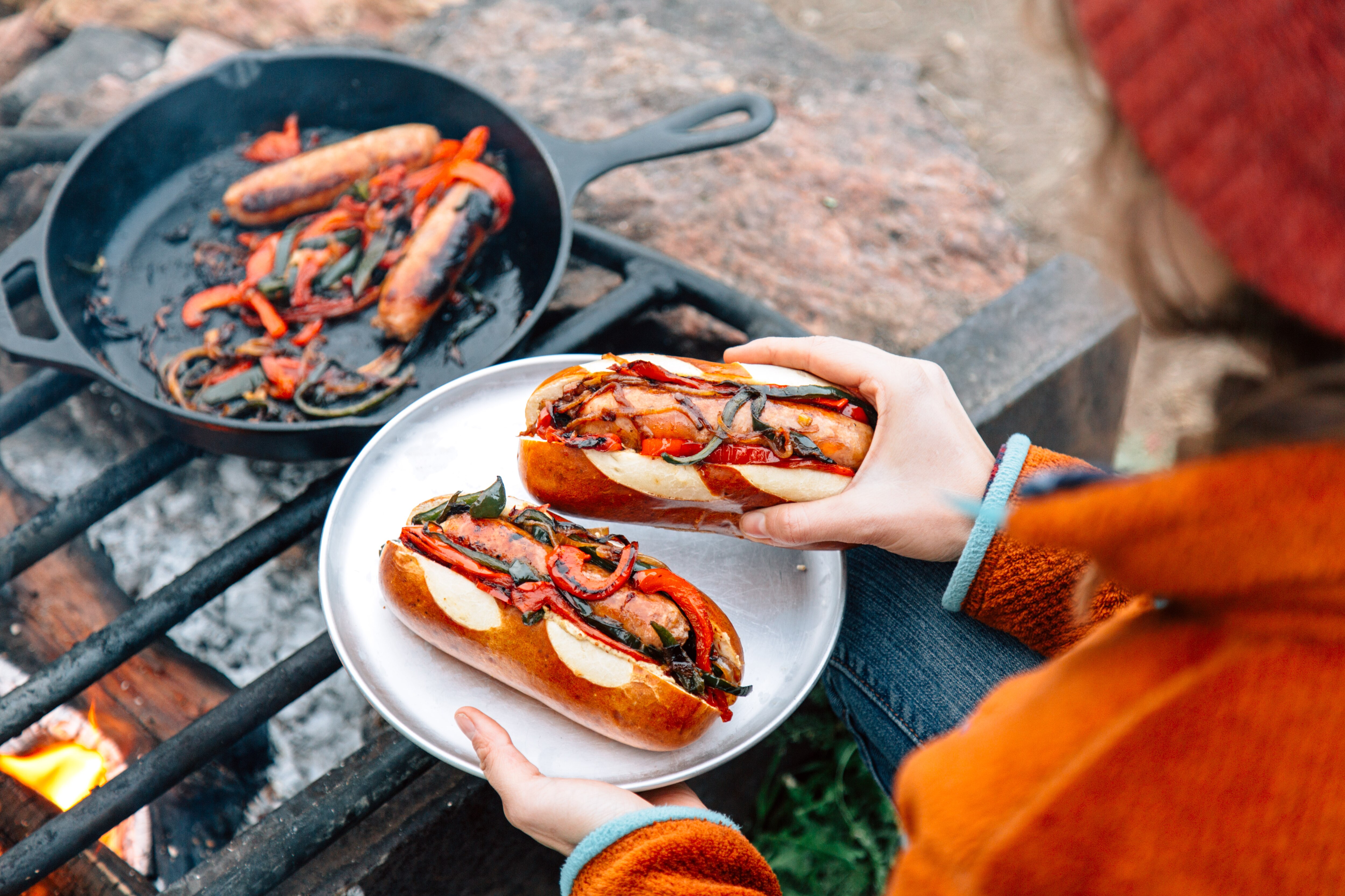 Person finishes making brats on a campfire