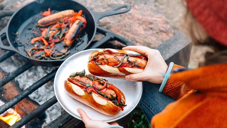 Person finishes making brats on a campfire