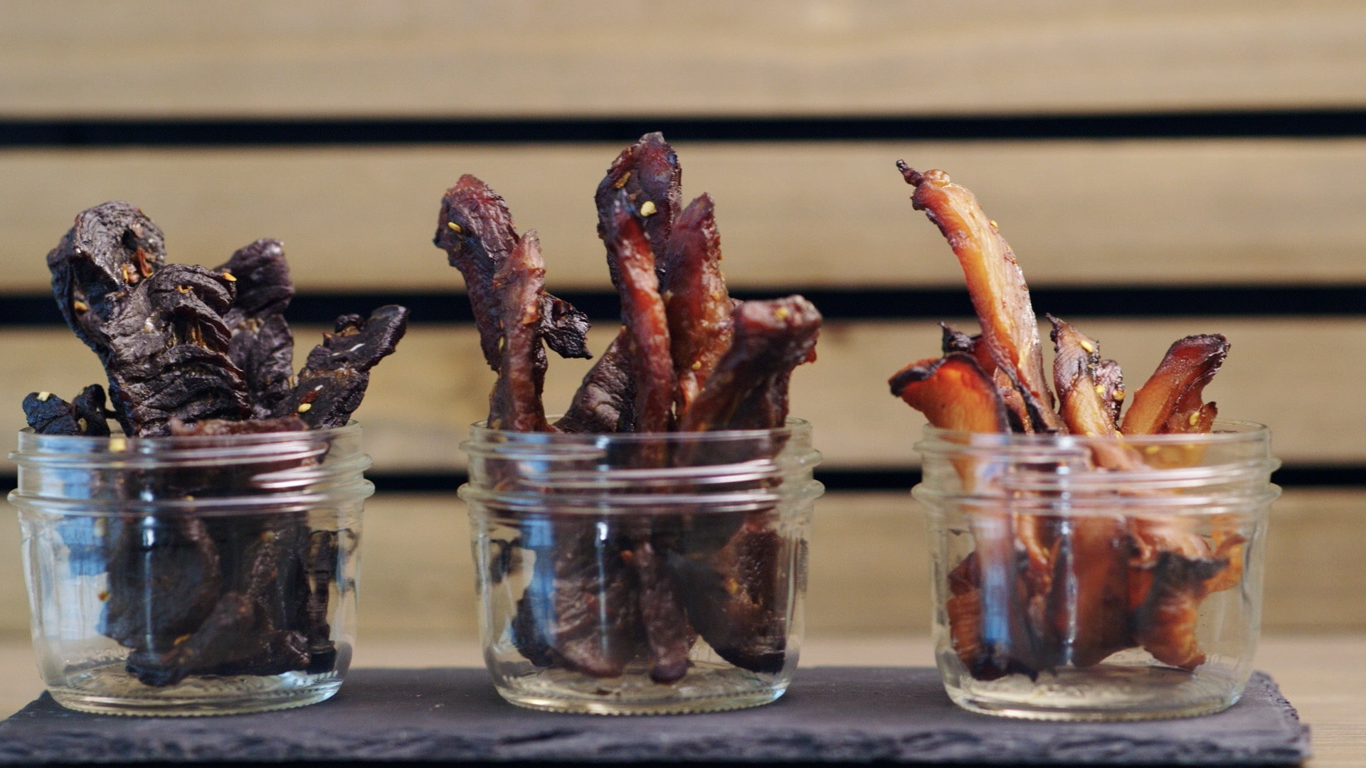 Three glass jars with different types of jerky.
