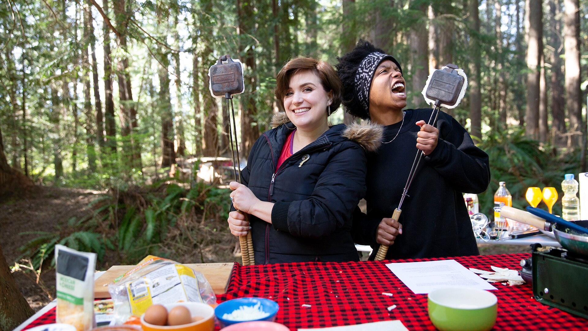 Two hungry people, each holding a pie iron with a just-cooked breakfast taco inside