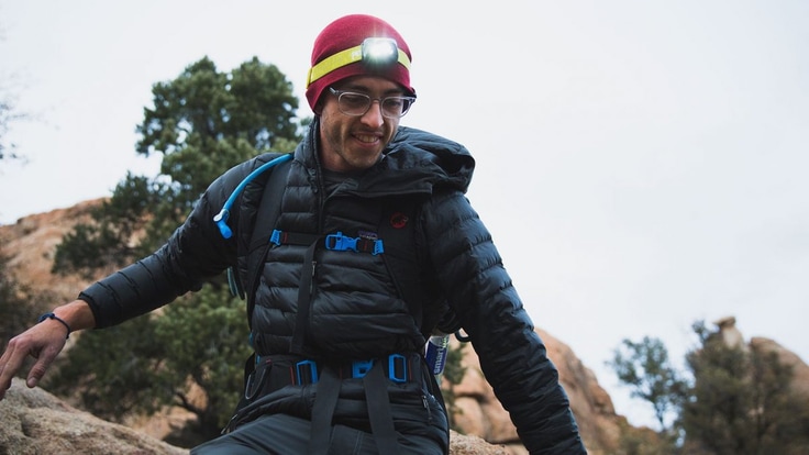 A hiker wears a beanie and a headlamp.