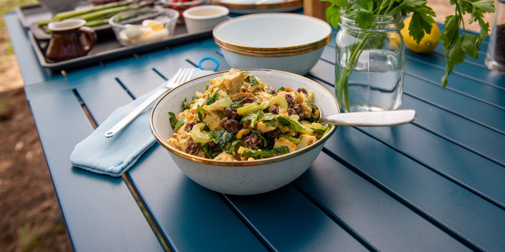 A bowl of curry chicken salad on a blue table